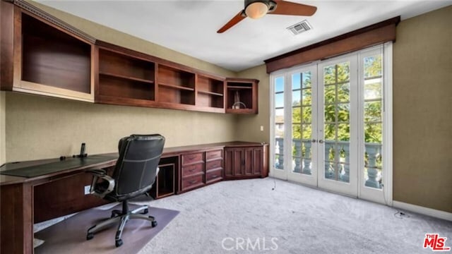 carpeted office space featuring ceiling fan, french doors, and built in desk