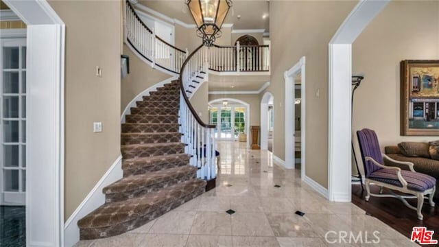 foyer featuring a towering ceiling, crown molding, and a chandelier