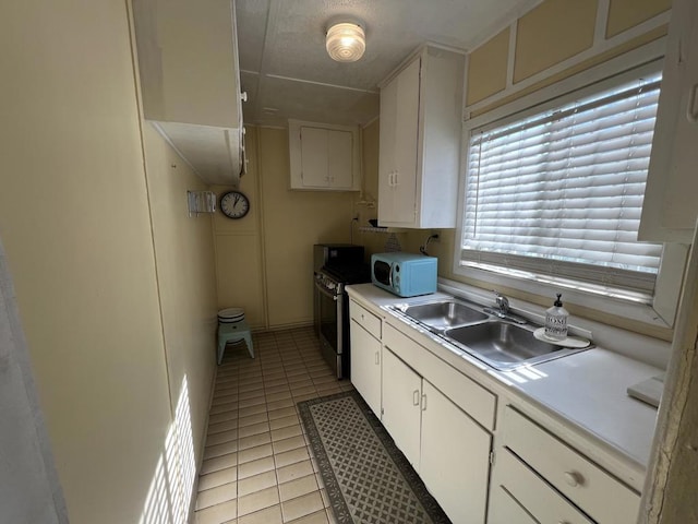 kitchen featuring sink, stainless steel electric stove, light tile patterned floors, and white cabinets