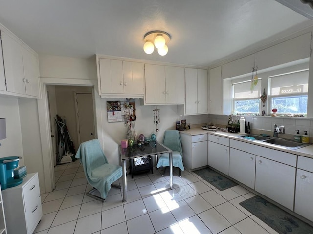 kitchen featuring light tile patterned floors, sink, and white cabinets