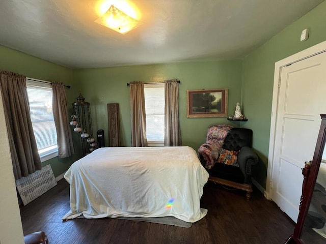 bedroom with multiple windows and dark hardwood / wood-style floors