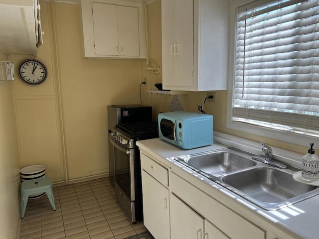 kitchen with white cabinetry, sink, gas stove, and light tile patterned floors