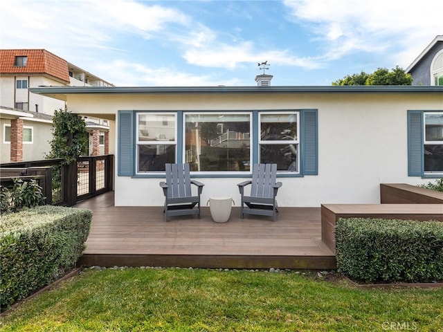 rear view of house featuring a deck and a lawn