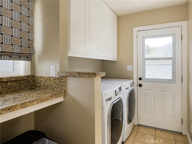 washroom with light tile patterned flooring, cabinets, and washer and dryer