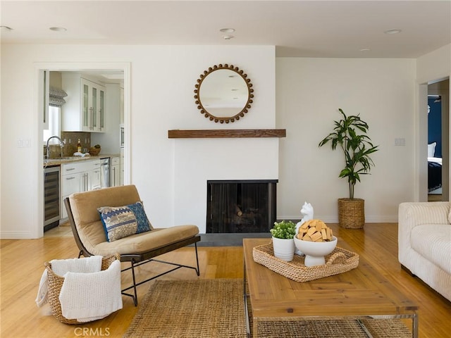 living room with indoor wet bar, beverage cooler, and light hardwood / wood-style flooring