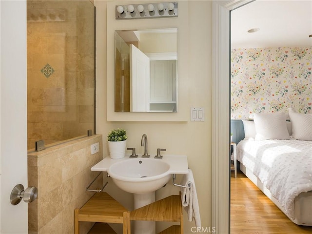 bathroom with a tile shower and wood-type flooring