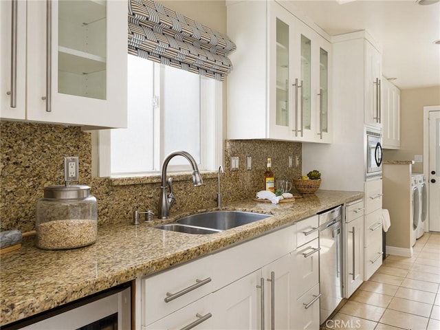 kitchen with light tile patterned flooring, sink, white cabinets, stainless steel appliances, and backsplash