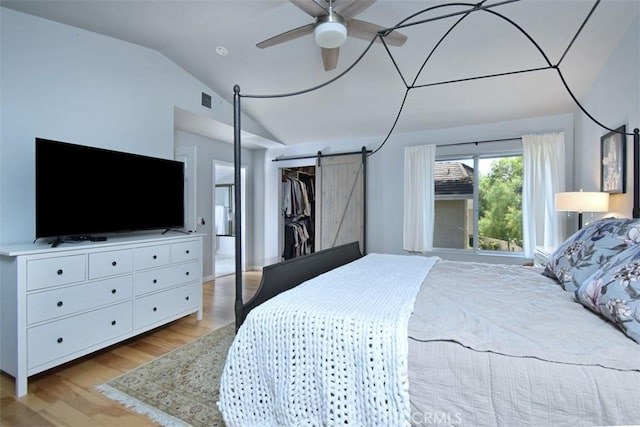 bedroom featuring light wood-type flooring, a closet, vaulted ceiling, ceiling fan, and a barn door