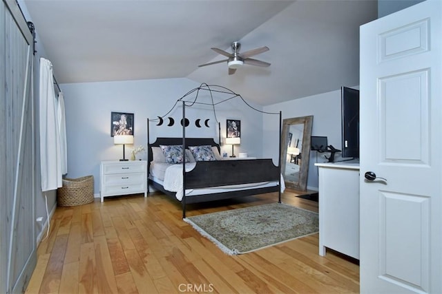 bedroom with ceiling fan, light hardwood / wood-style floors, lofted ceiling, and a barn door