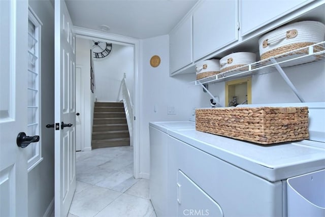 laundry area featuring washing machine and dryer, cabinets, and light tile patterned flooring