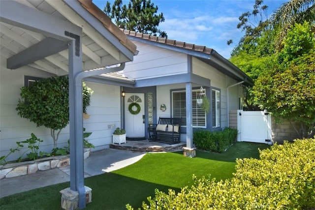 view of exterior entry with a yard and a porch