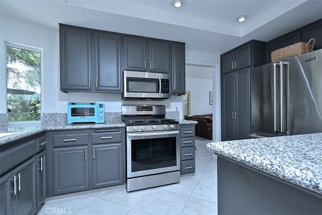 kitchen with light tile patterned floors, stainless steel appliances, and light stone counters