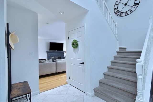 stairs featuring tile patterned flooring and a brick fireplace