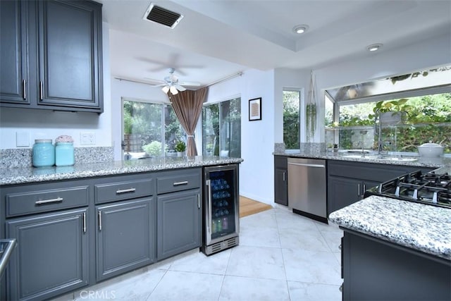 kitchen featuring stainless steel dishwasher, wine cooler, ceiling fan, and light stone countertops