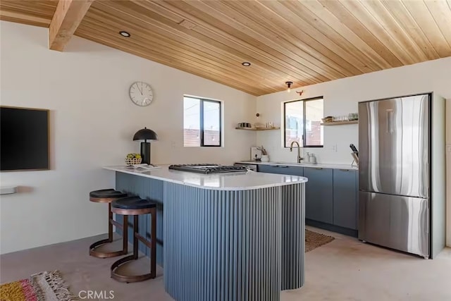 kitchen featuring sink, a kitchen bar, appliances with stainless steel finishes, and wooden ceiling