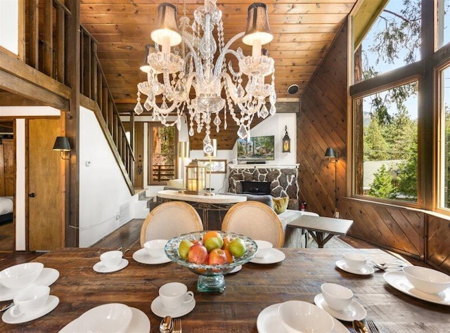 dining space featuring high vaulted ceiling, wooden walls, a chandelier, and wooden ceiling