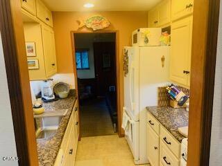 kitchen featuring white refrigerator, sink, and dark stone counters