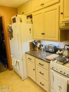 kitchen with white appliances and dark stone counters