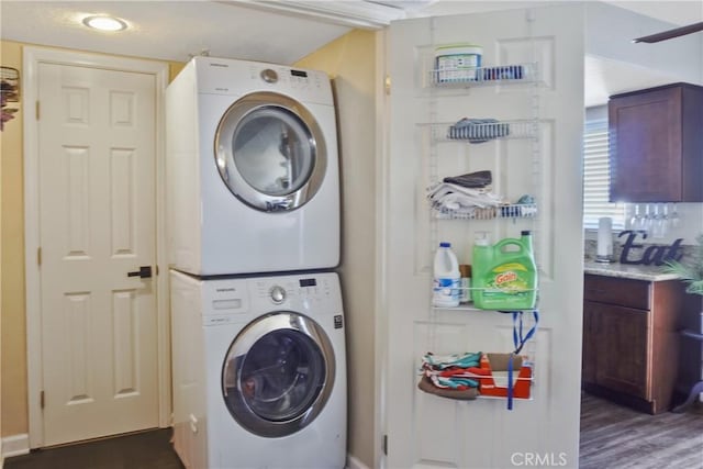 washroom with dark hardwood / wood-style flooring and stacked washer and dryer