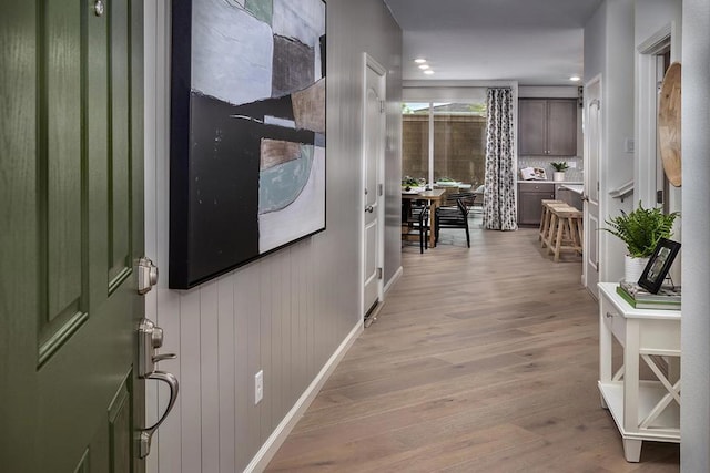 hallway with wood walls and light hardwood / wood-style flooring