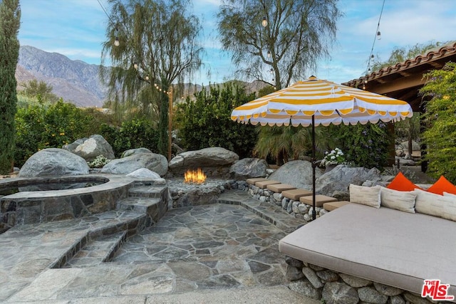 view of patio with a mountain view and a fire pit