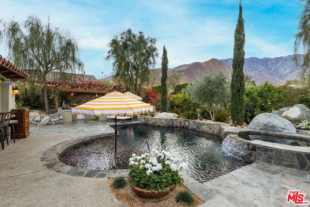 view of swimming pool with pool water feature, a mountain view, and a patio