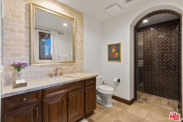 bathroom with tile patterned flooring, vanity, tiled shower, and toilet