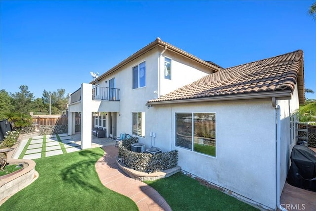 rear view of house featuring a patio area, a balcony, and a yard