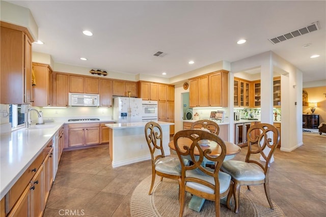 kitchen featuring white appliances, beverage cooler, a center island, decorative backsplash, and sink