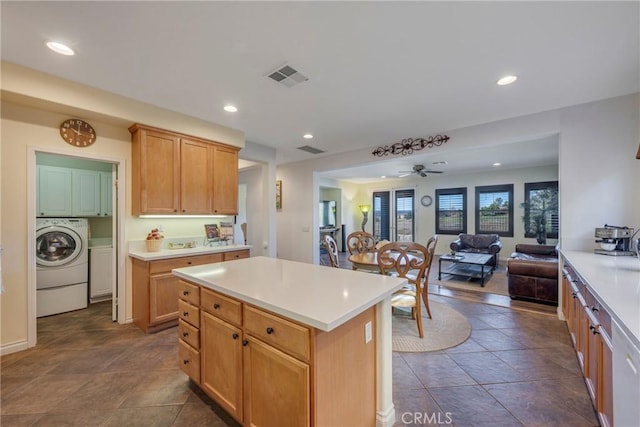 kitchen with ceiling fan, light brown cabinetry, a center island, and washer / clothes dryer