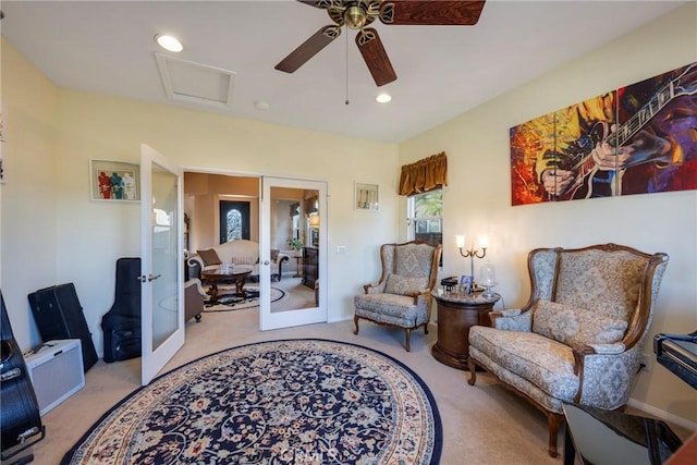 sitting room with ceiling fan, light colored carpet, and french doors