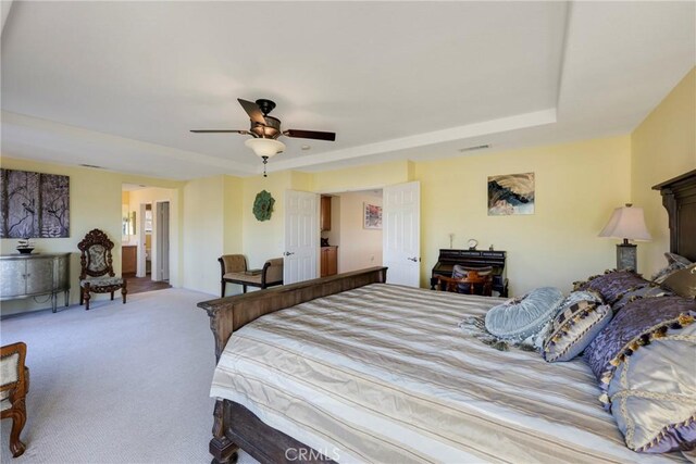 carpeted bedroom featuring ceiling fan and a tray ceiling