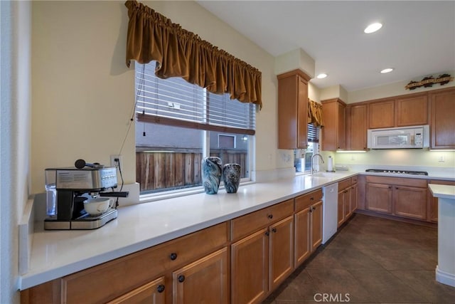 kitchen with stainless steel dishwasher, gas cooktop, sink, and dark tile patterned floors