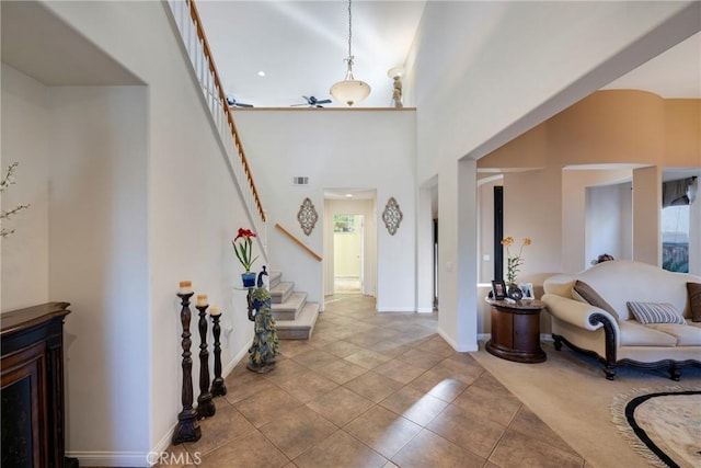 tiled entrance foyer featuring ceiling fan and a towering ceiling