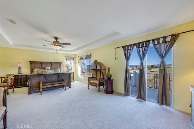 bedroom with a raised ceiling, access to outside, and multiple windows