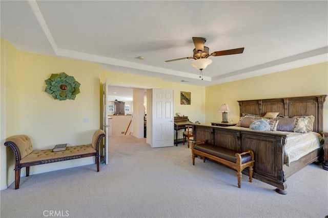 carpeted bedroom with ceiling fan and a tray ceiling