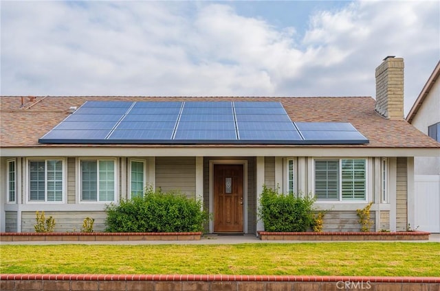 view of front of home with a front yard and solar panels