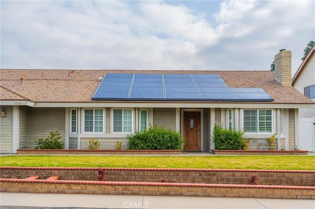 single story home with a front yard and solar panels