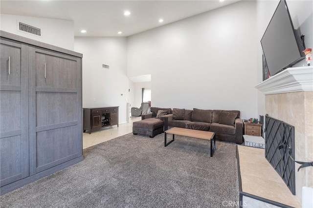 carpeted living room featuring high vaulted ceiling and a tile fireplace