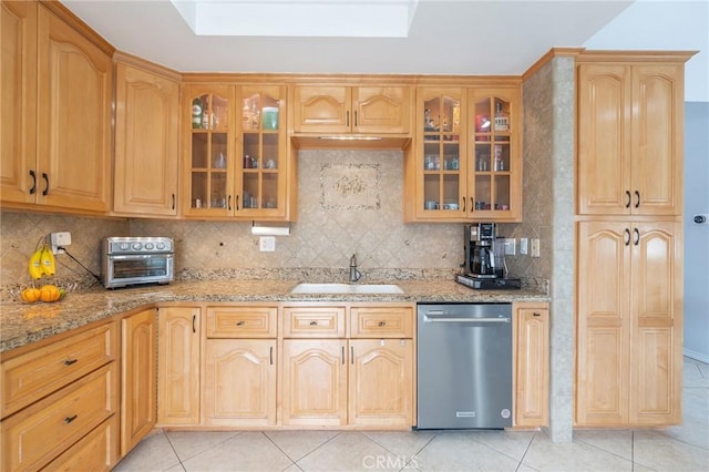 kitchen with dishwasher, light stone countertops, sink, and light tile patterned flooring