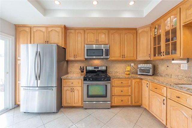 kitchen featuring appliances with stainless steel finishes, a raised ceiling, and light stone countertops