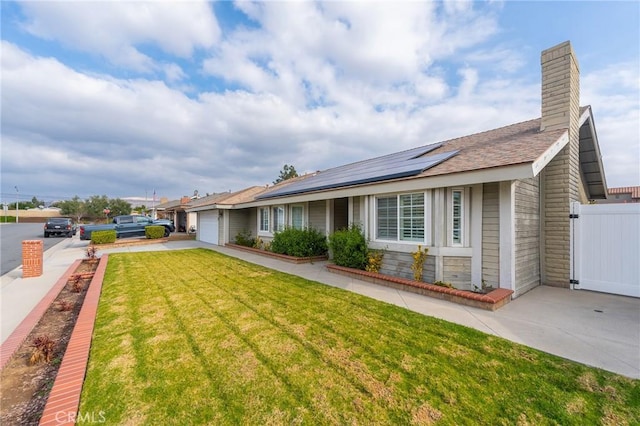 exterior space with a garage, a yard, and solar panels