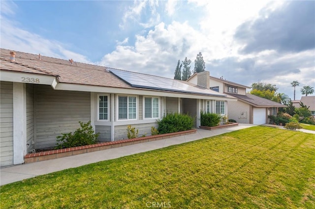 view of front of house featuring a garage, a front lawn, and solar panels