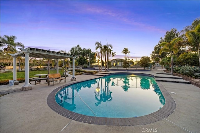 pool at dusk with a pergola and a patio area