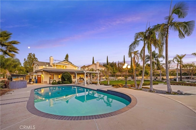 pool at dusk featuring a patio