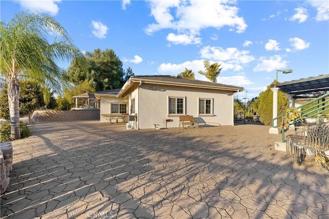 rear view of house featuring a pergola and a patio