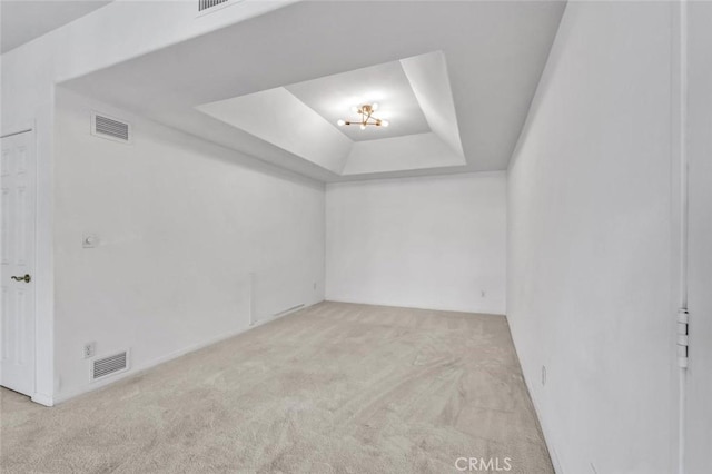 carpeted empty room featuring a raised ceiling