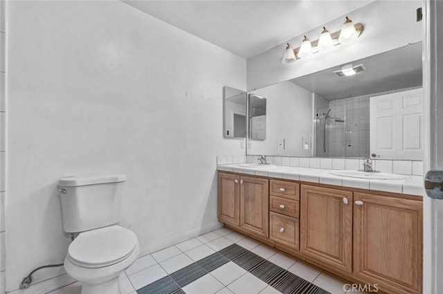 bathroom with tile patterned floors, tiled shower, toilet, and vanity