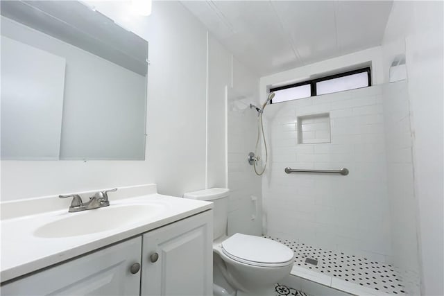 bathroom featuring toilet, vanity, and a tile shower