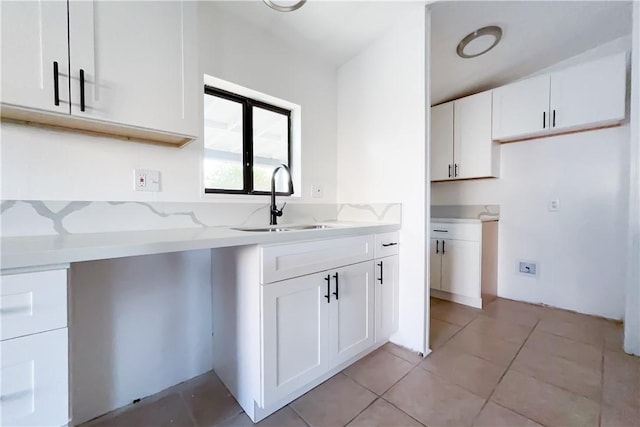 kitchen featuring light stone countertops, light tile patterned flooring, white cabinets, and sink